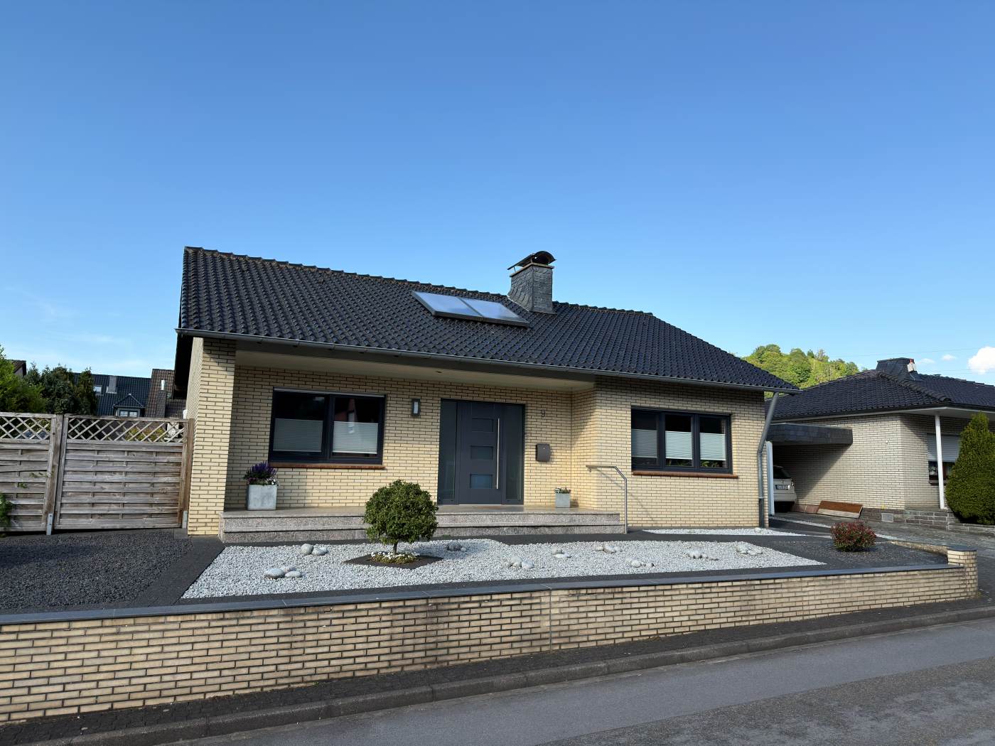 Straßenansicht des freistehenden Bungalows mit Klinkerfassade und Vorgarten
